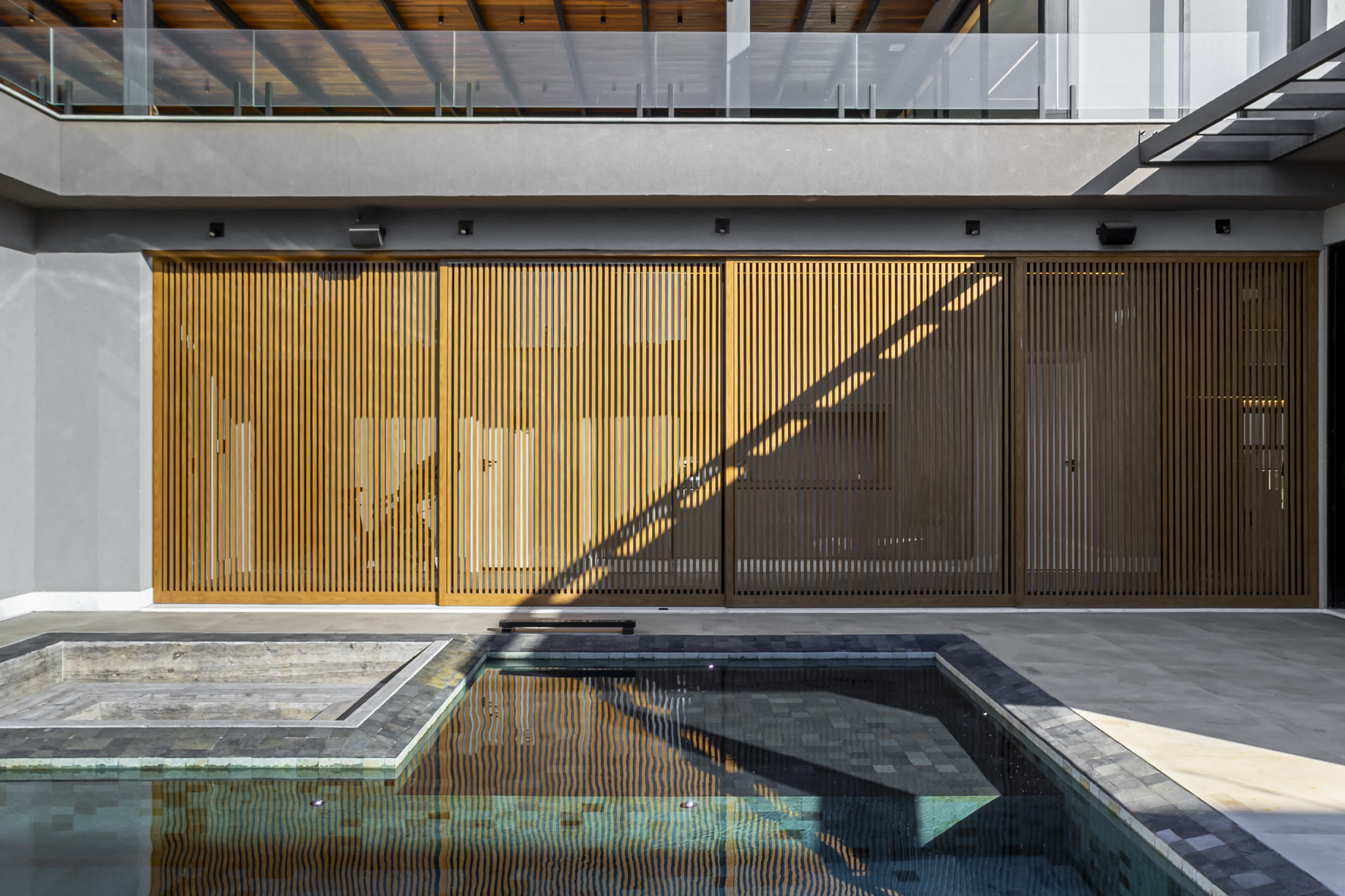 Fachada com madeira e piscina em residência autoral